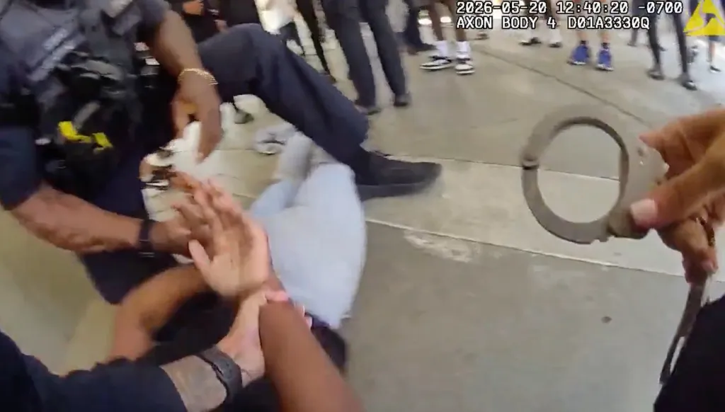 Body camera footage showing police officers apprehending a person on the ground while holding handcuffs.