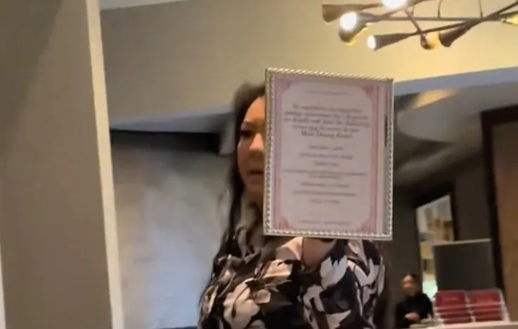 A woman holding up a sign detailing dress code requirements.