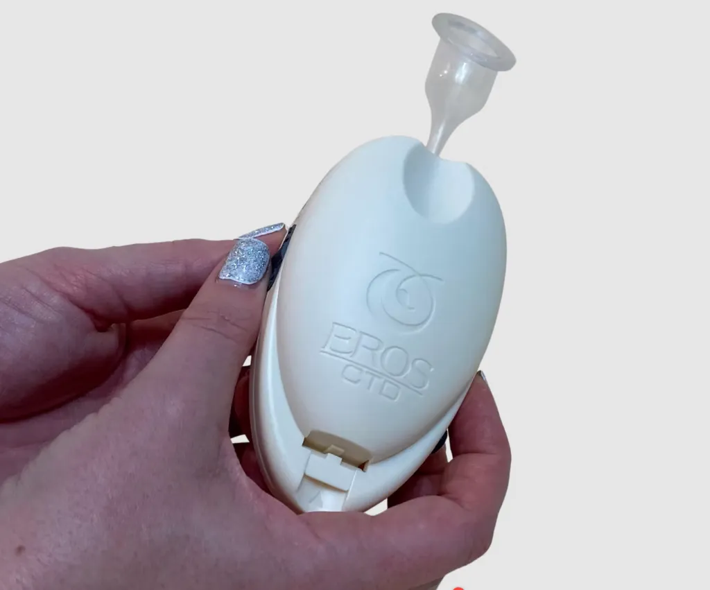 A hand holding an FDA-approved EROS clitoral therapy device, a white, oval-shaped device with 