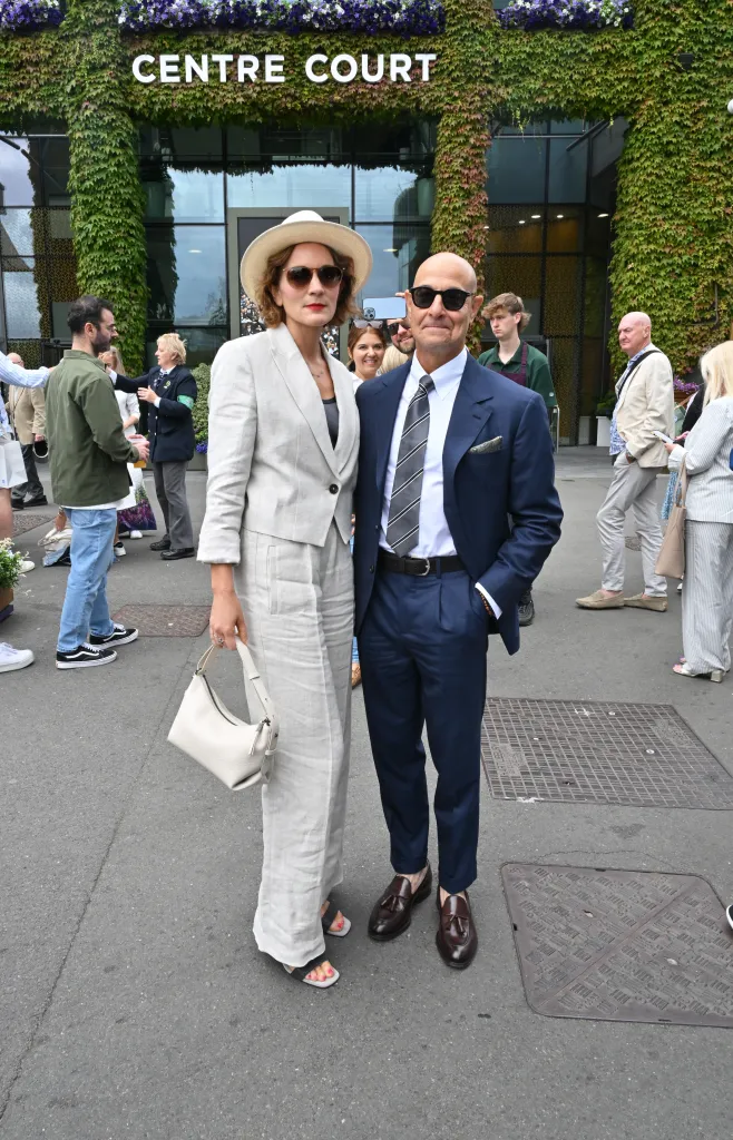 Felicity Blunt and Stanley Tucci at Wimbledon, with Blunt in a light suit and Tucci in a dark suit.
