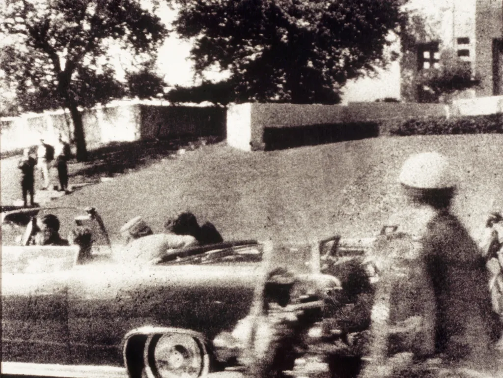 First Lady Jacqueline Kennedy leans over her husband, President John F. Kennedy, in a convertible during his assassination in Dallas.