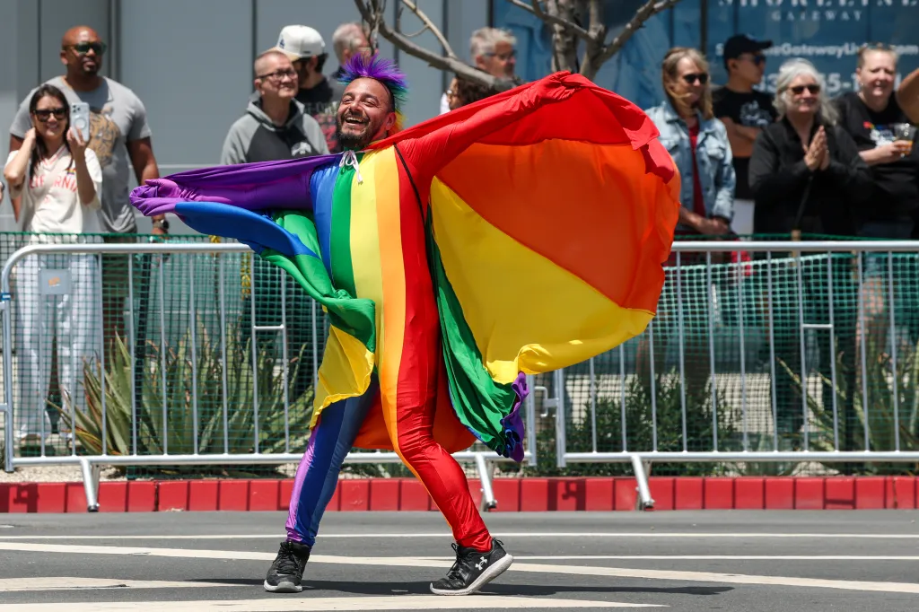 Frankie Barcenan of the Trans Latina Coalition dances at the Long Beach Pride Parade in a rainbow-colored outfit and matching mohawk.