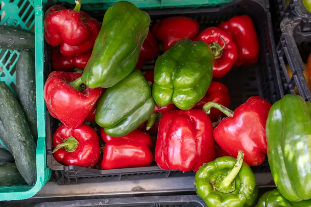 Red and green bell peppers in a market crate.