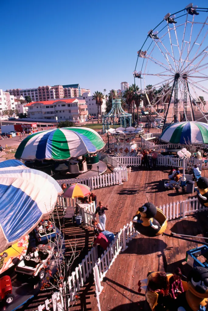 A fun fair with a Ferris wheel and other rides on Santa Monica Pier.