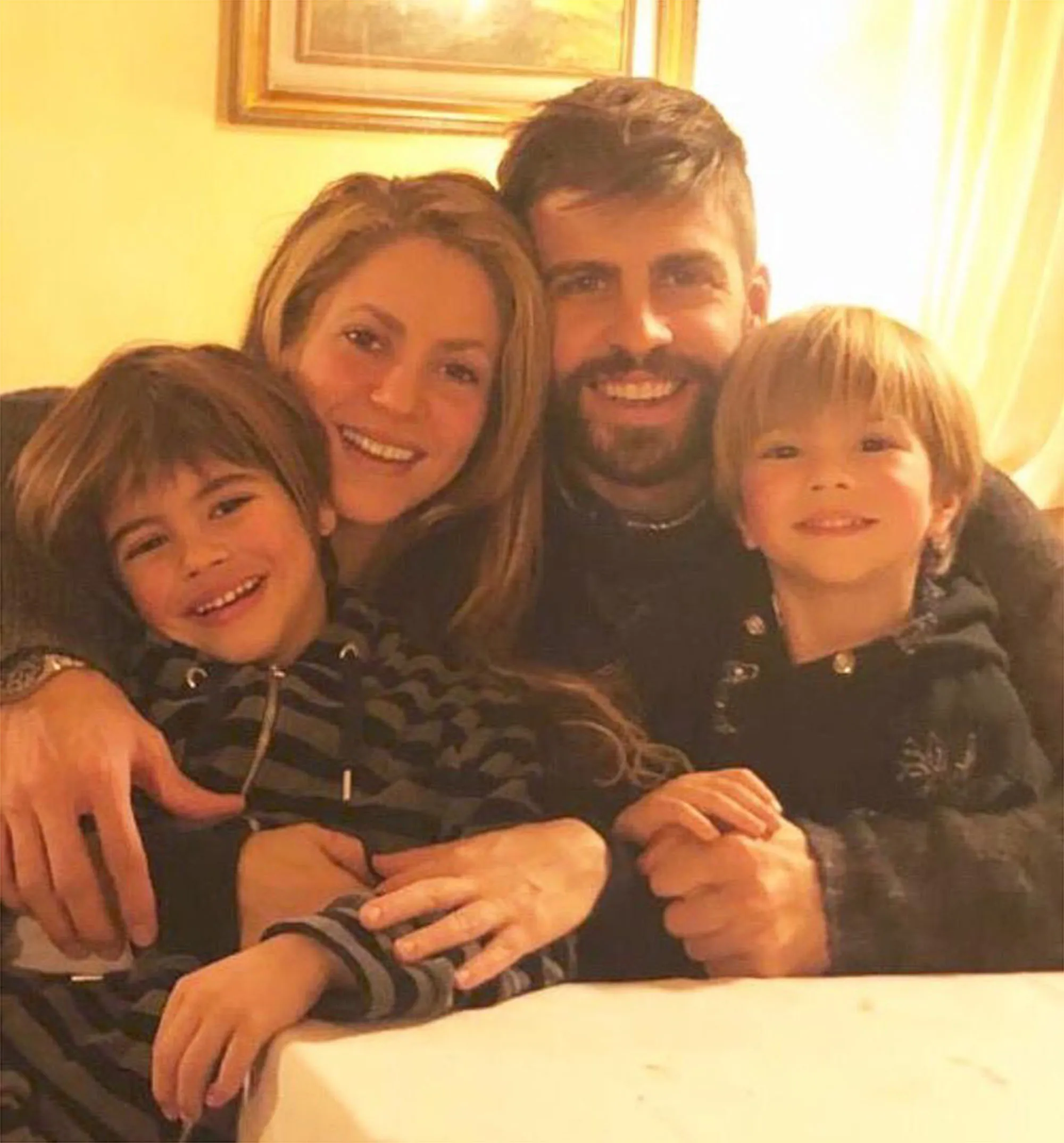 Shakira and Gerard Piqué with their two sons smiling at the camera.