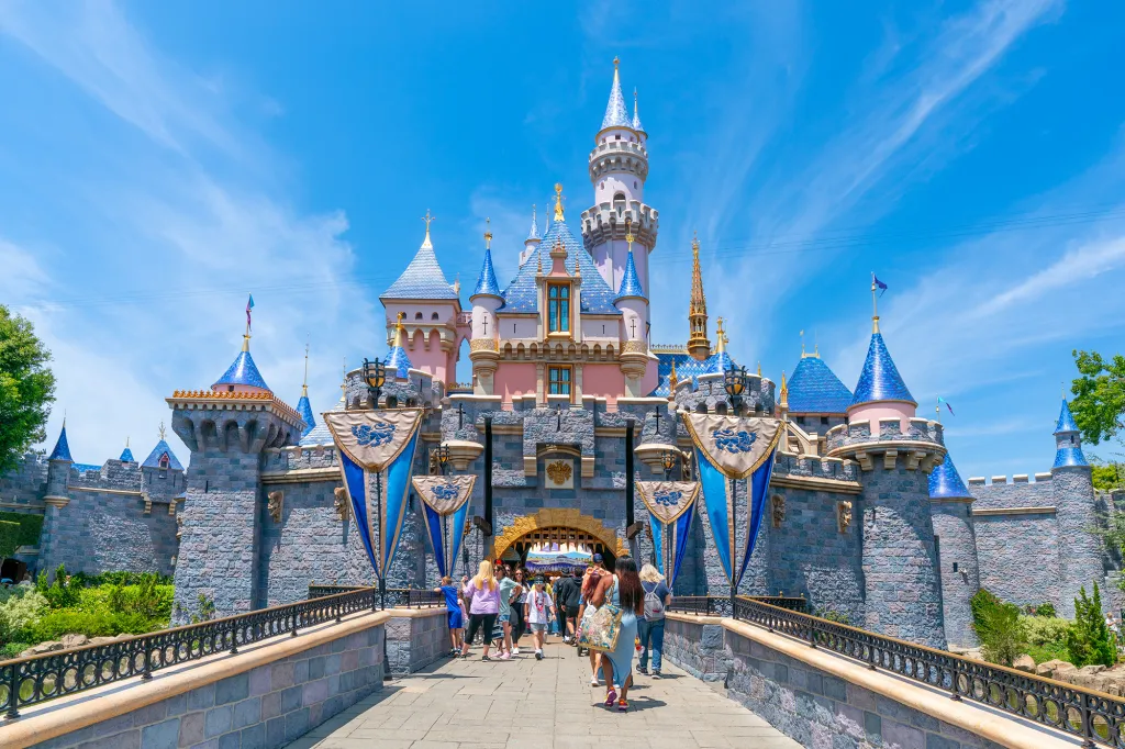 Sleeping Beauty Castle at Disneyland, with people crossing the bridge towards its entrance.