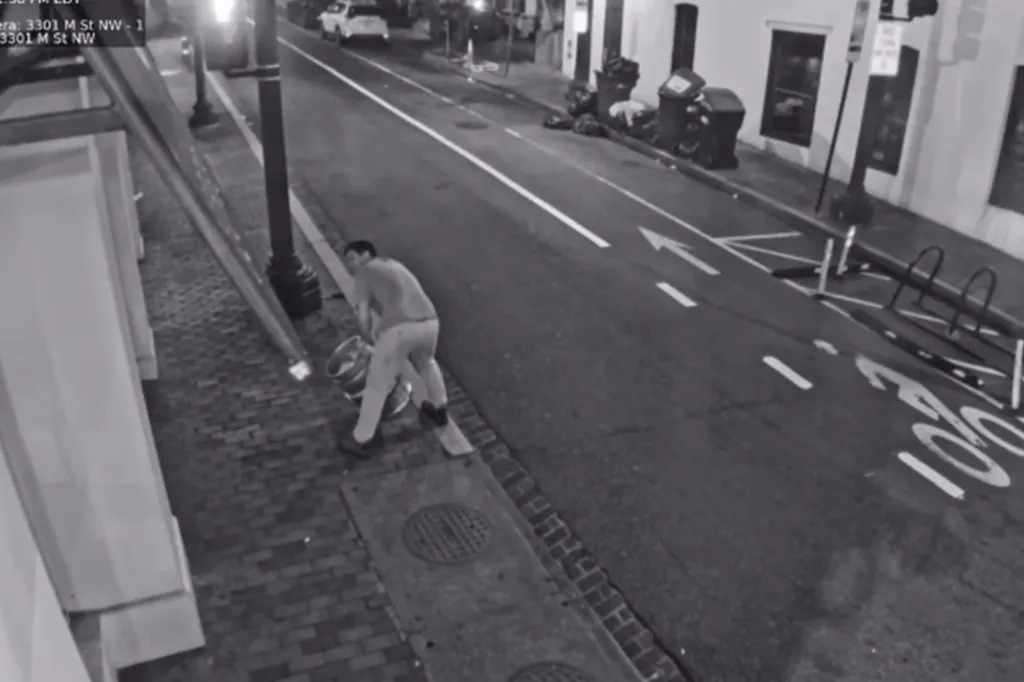 Security footage of a man carrying a beer keg on a sidewalk.