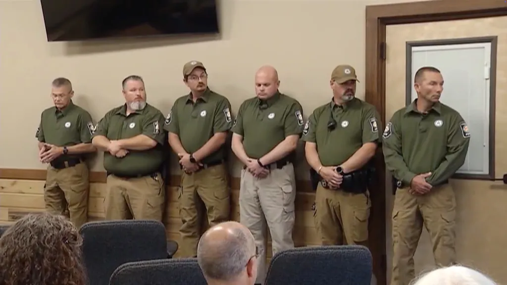 Six Cohutta police officers in olive shirts and khaki pants standing in a room.