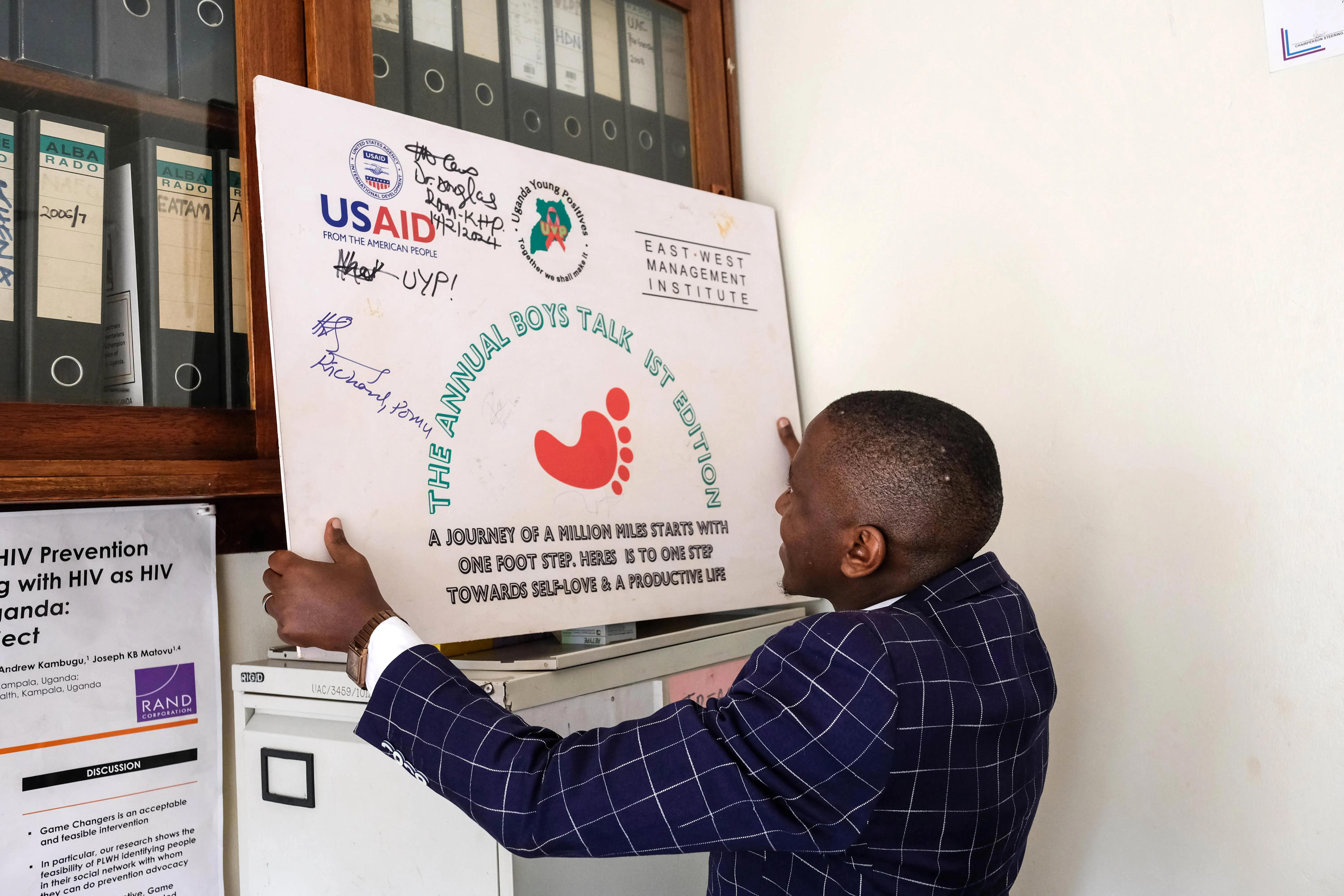 A staff member at an HIV outreach organization holds a poster inscribed with the USAID logo. A staff member at an HIV outreach organization holds a poster inscribed with the USAID logo.