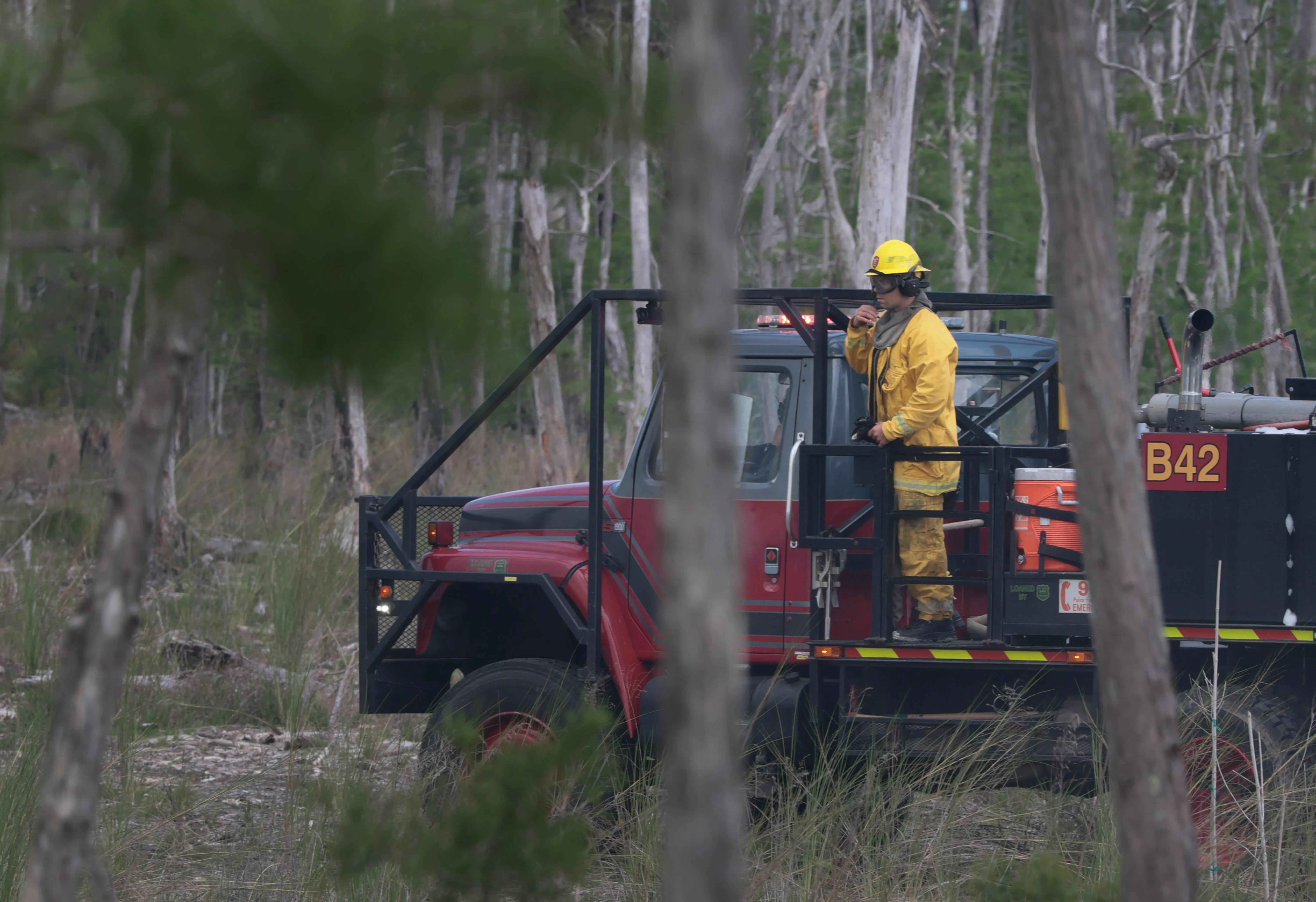 firefighter in a vehicle surrounded by a forest with smoke in the air