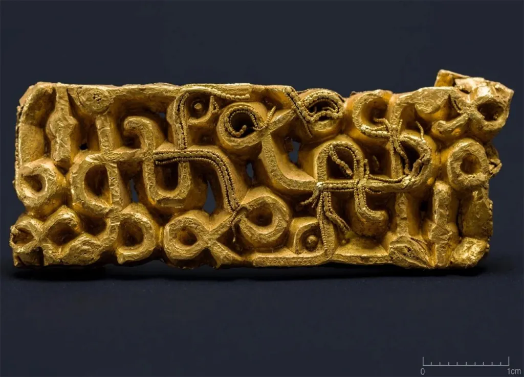 Golden sword scabbard fitting with intricate curvilinear designs.