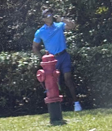 Golfer Tiger Woods stands by a fire hydrant.