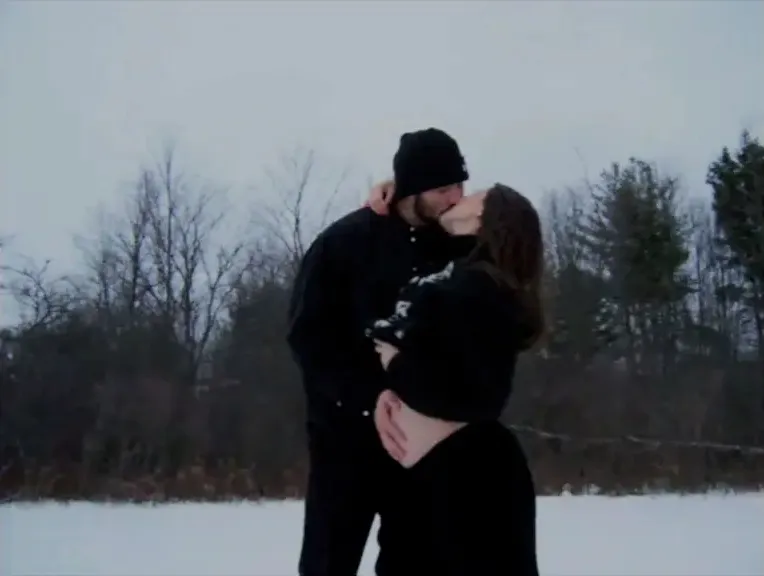 Hailee Steinfeld and Josh Allen kissing in a snowy landscape.