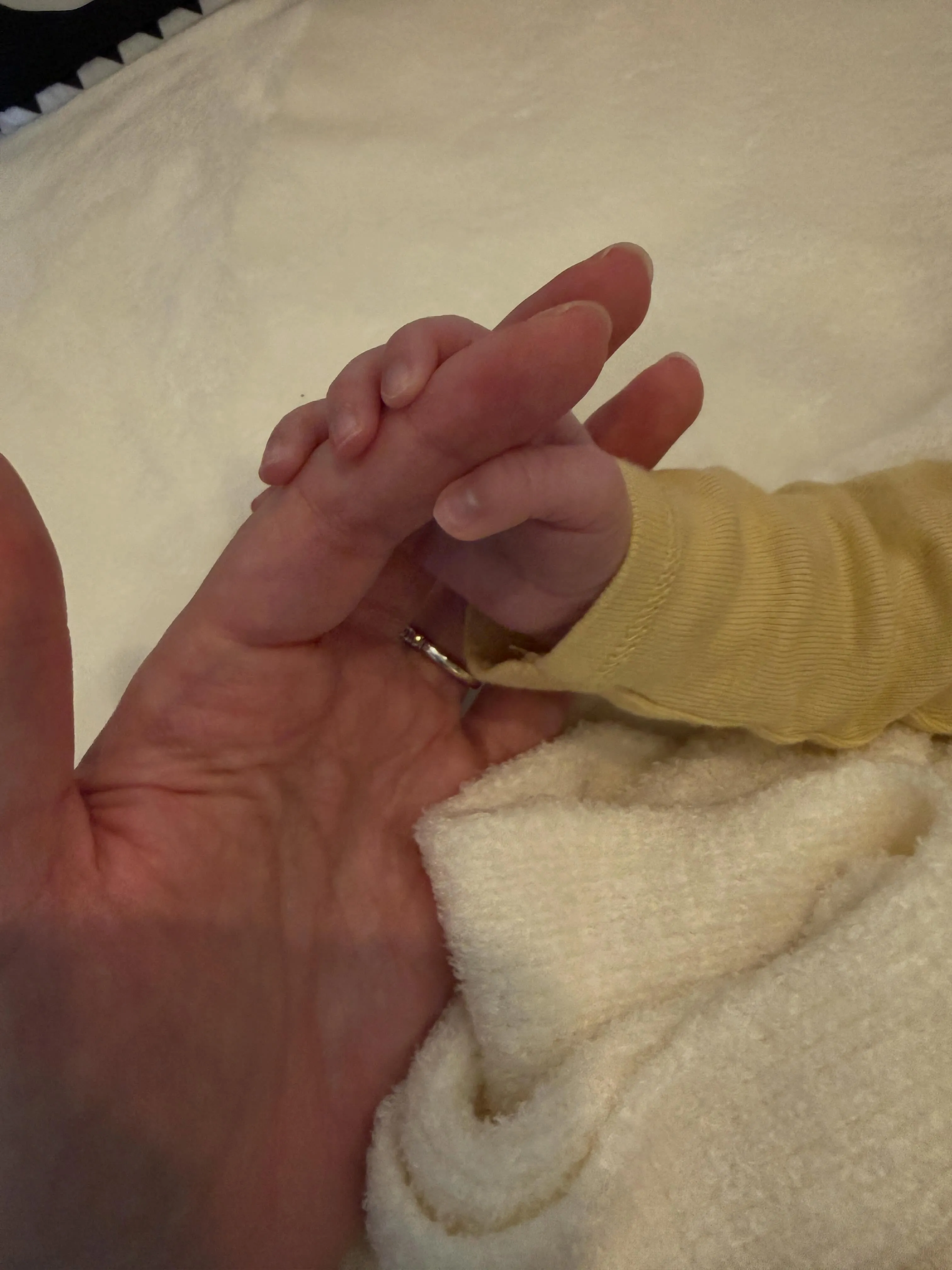 Hailie Steinfield holding a baby's hand, who is wearing a yellow long-sleeved shirt.