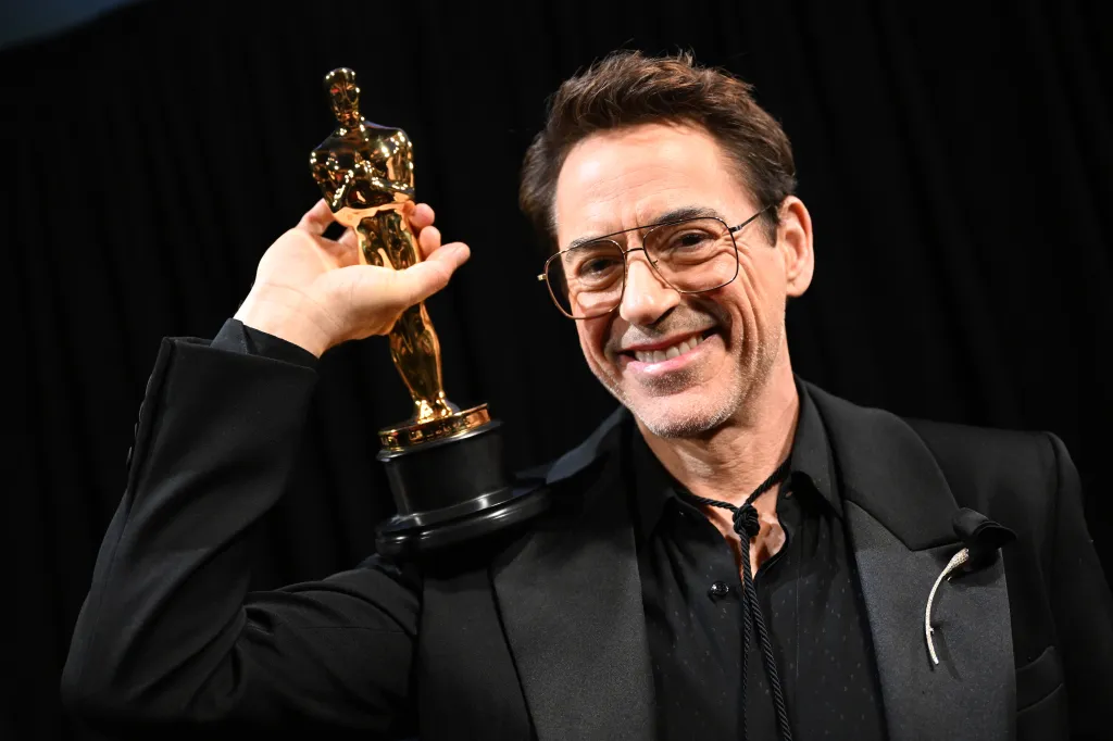 Robert Downey Jr. smiles, holding his Oscar trophy.