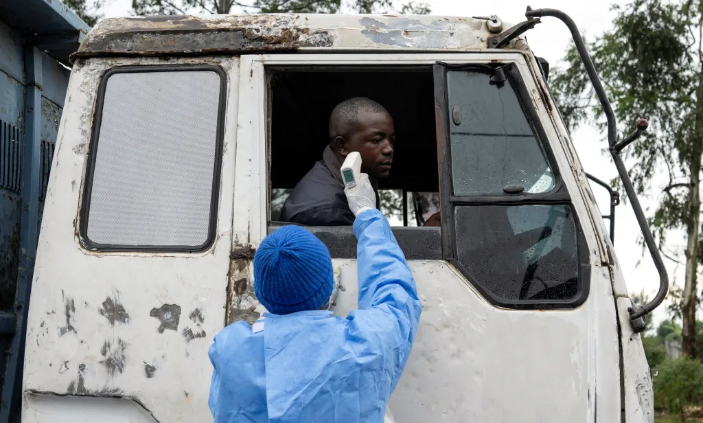 A health worker checks the temperature of a truck driver.
