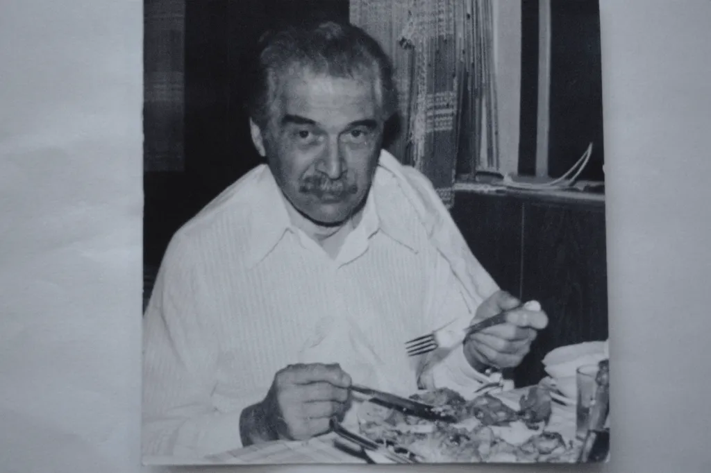 Black and white photo of Josef Mengele with a mustache, eating at a table.