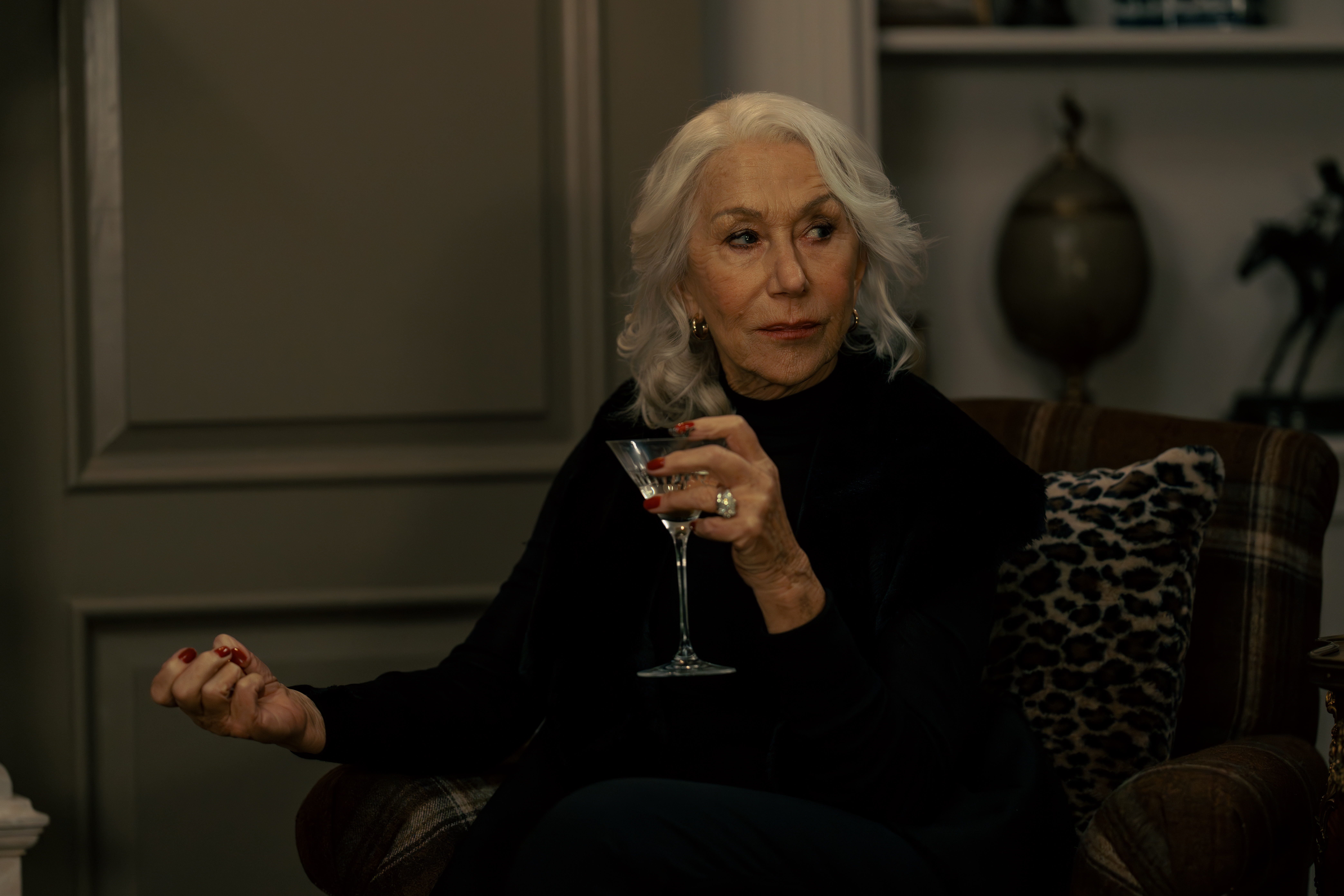 Helen Mirren as Maeve Harrigan holding a martini glass, looking off to the side.