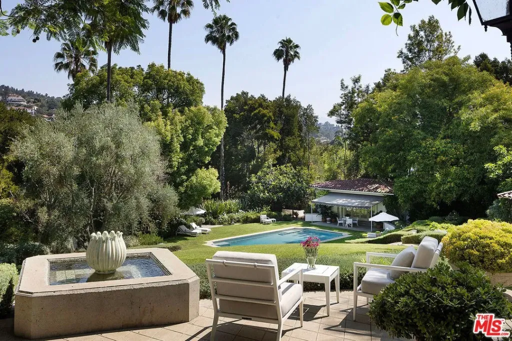A view of the backyard of Angelina Jolie's Los Angeles estate featuring a pool, lush greenery, and outdoor seating.
