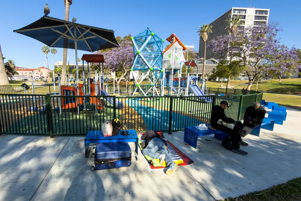 Homeless people rest near a playground in MacArthur Park, Los Angeles.