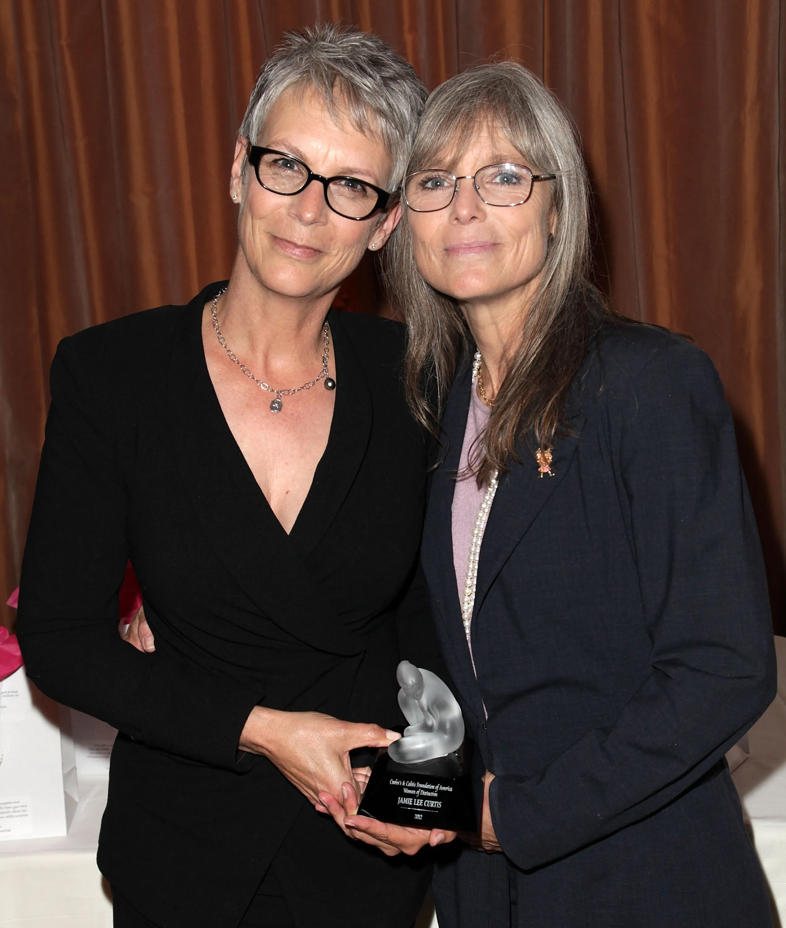 Jamie Lee Curtis and sister Kelly Lee Curtis holding the Crohn's & Colitis Foundation of America's Woman of Distinction award.
