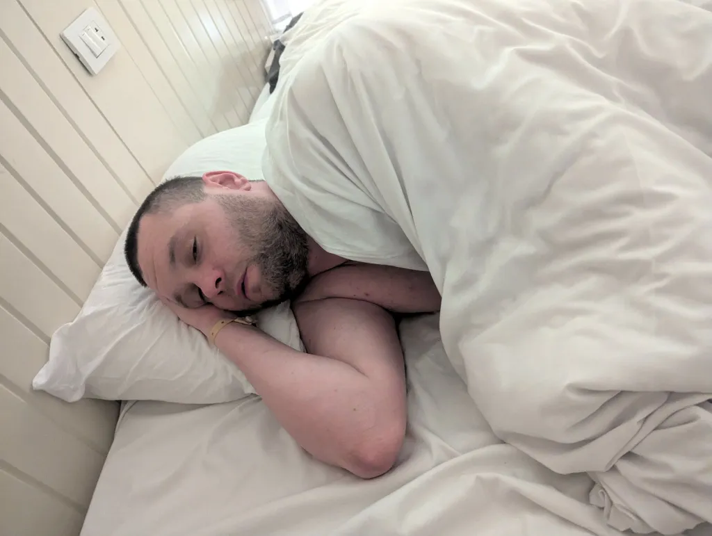 Man lying in bed looking ill.
