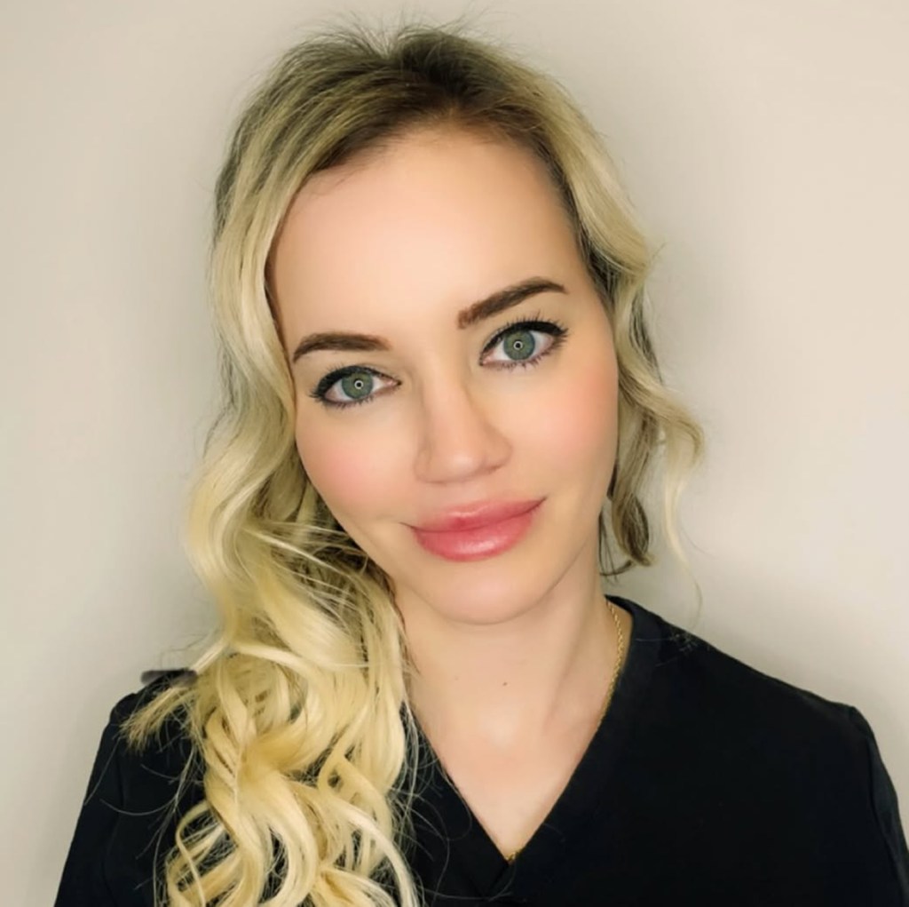 Katherine Torbick, a woman with long blonde hair and green eyes, looks at the camera.