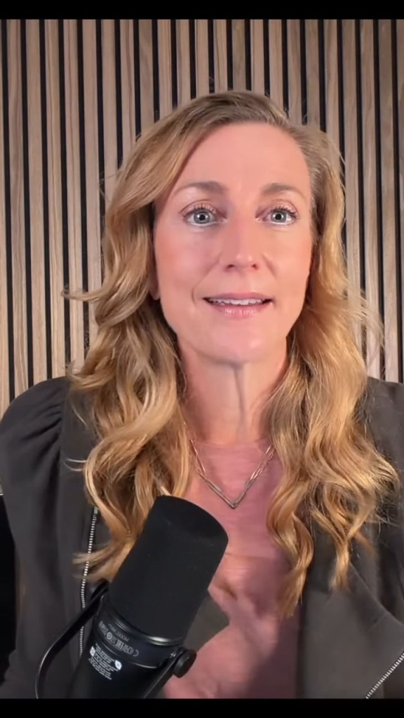 A blonde woman with a microphone is presenting.