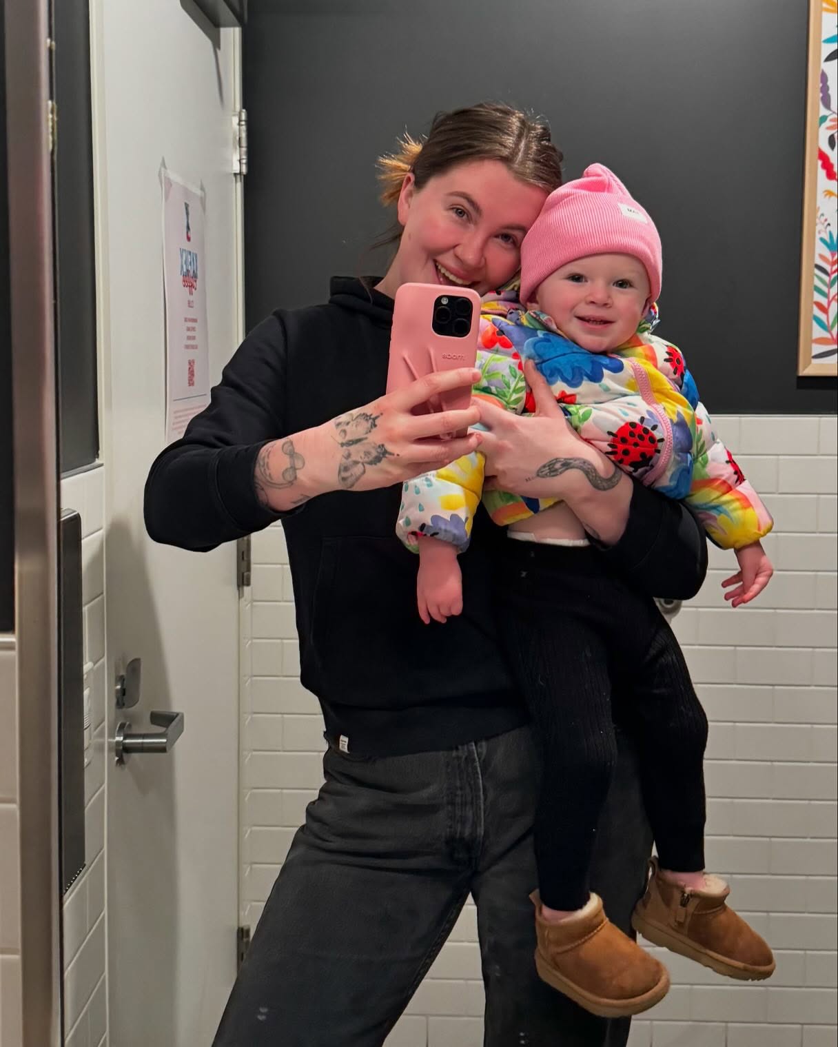 Ireland Baldwin holding her baby, both smiling, in a bathroom selfie.