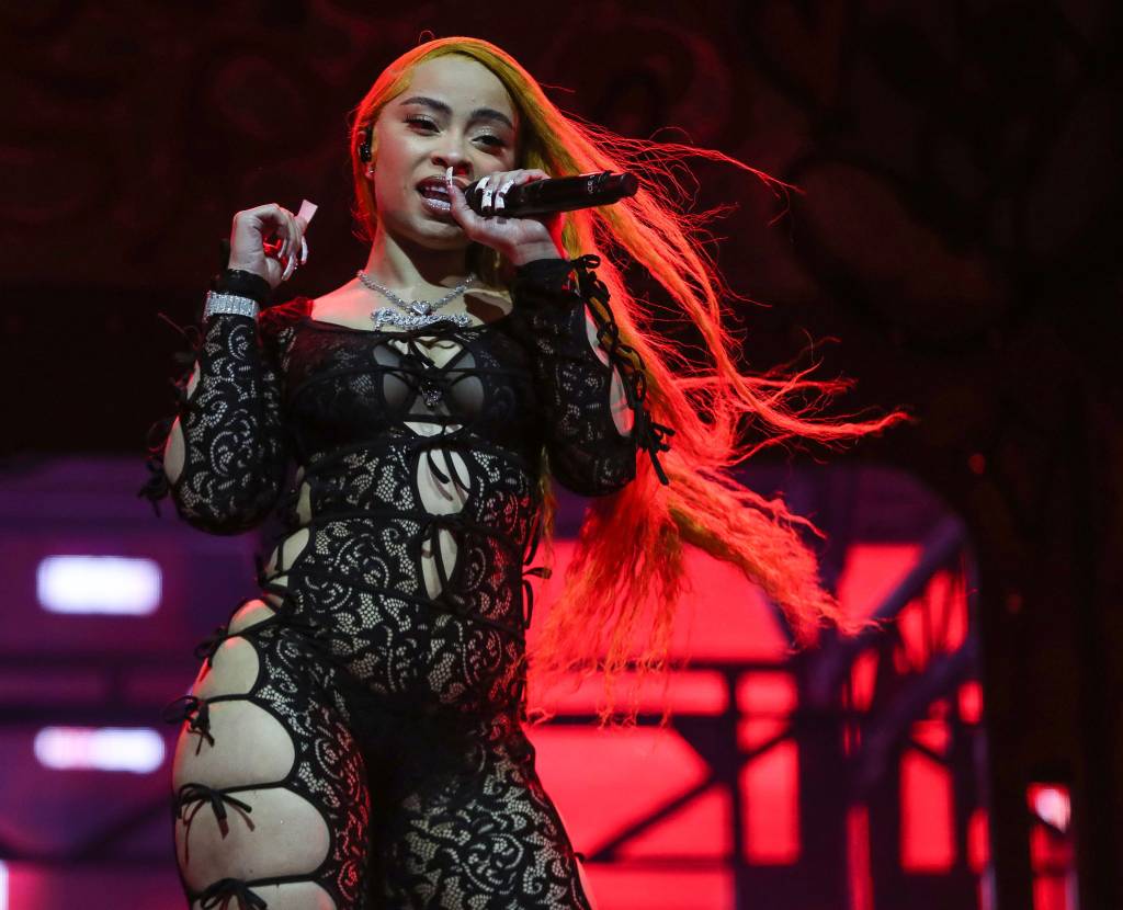 Ice Spice performing in a black lace outfit with long orange hair at the Coachella Valley Music and Arts Festival.