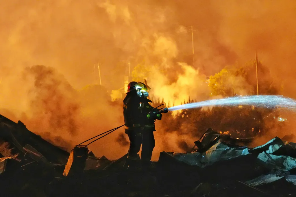 Firefighter spraying water on a fire at a fireworks factory.