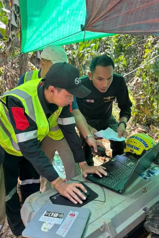 Rescuers use a laptop and two-way radio to coordinate efforts to reach people trapped in a cave in Xaisomboun province, Laos.