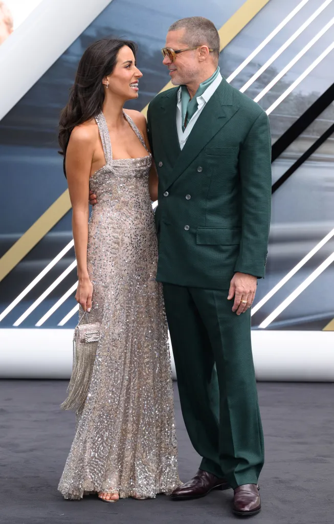 Ines de Ramon in a sparkly gown and Brad Pitt in a green suit pose together at the 