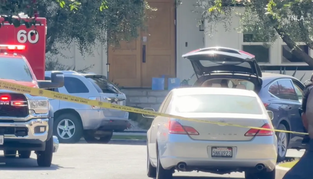 Crime scene with police tape across vehicles and a house in the background.