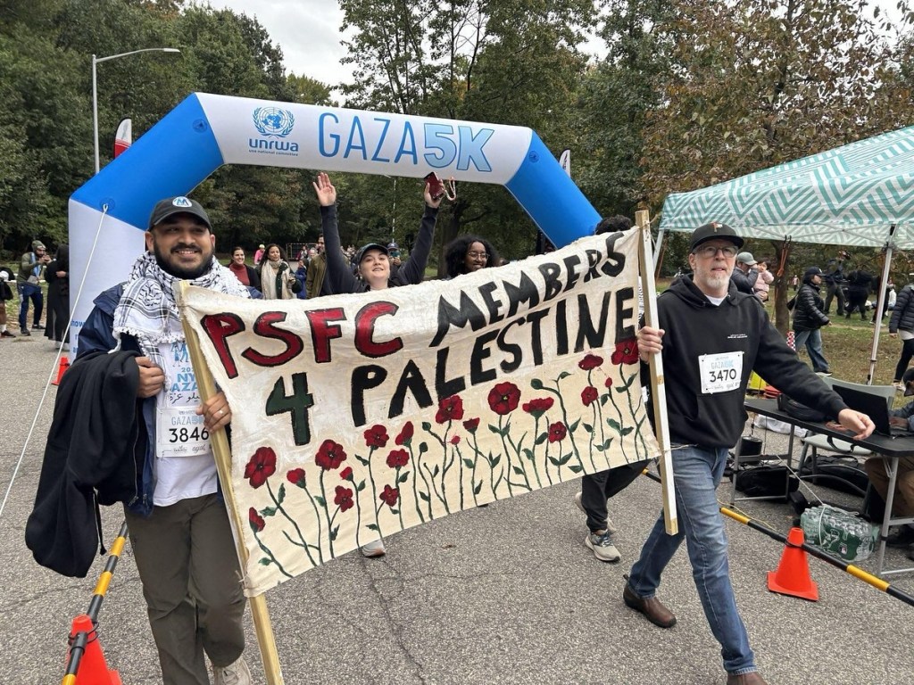 People march under a banner reading 