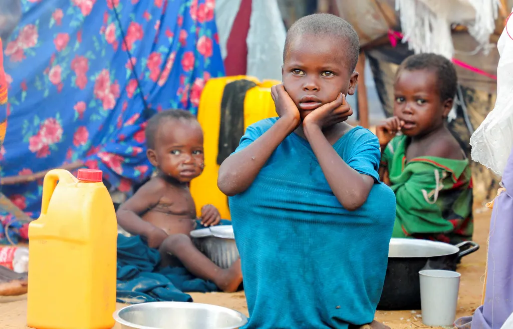 Three internally displaced children sitting outside makeshift shelters in Kahda district of Mogadishu, Somalia.