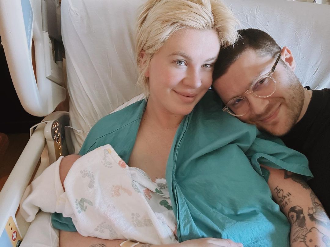 Ireland Baldwin and a man lying in a hospital bed with their newborn baby.