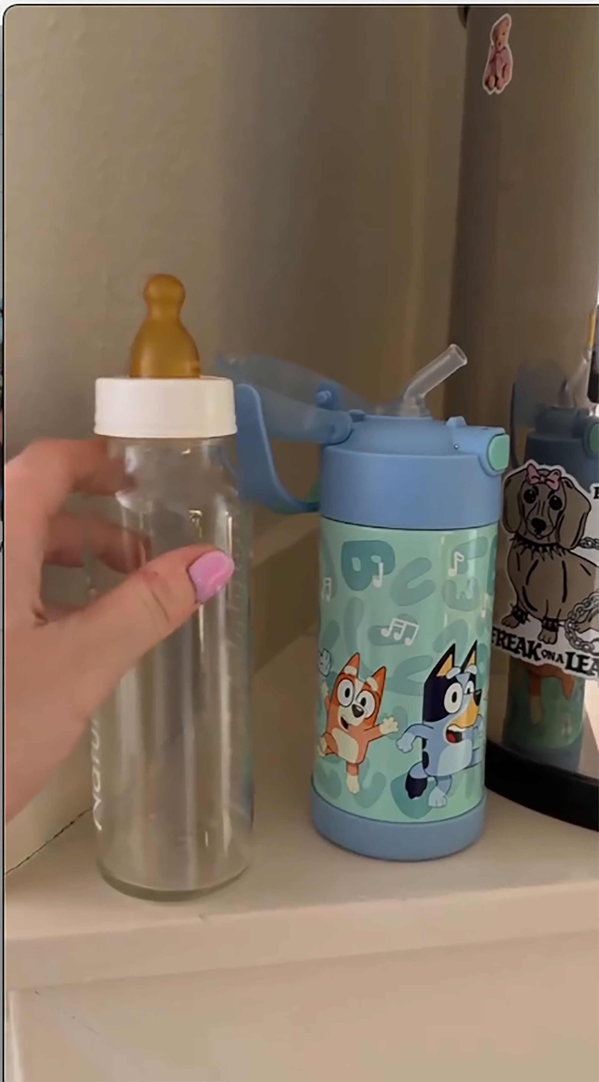 Ireland Baldwin holds a baby bottle next to a toddler's Bluey-themed water bottle.