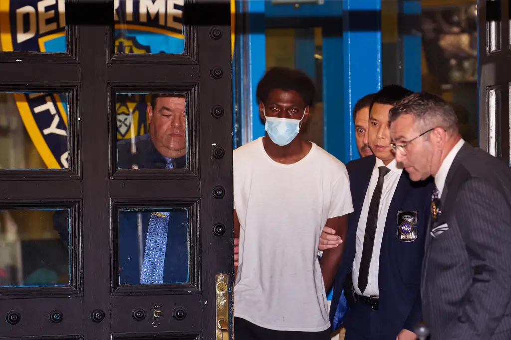 Argro is wearing a mask as authorities escort him. 