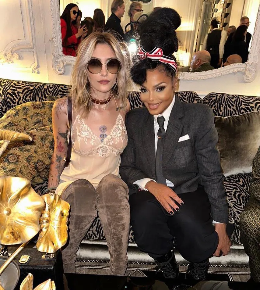 Paris Jackson and Janet Jackson posing together on a couch.