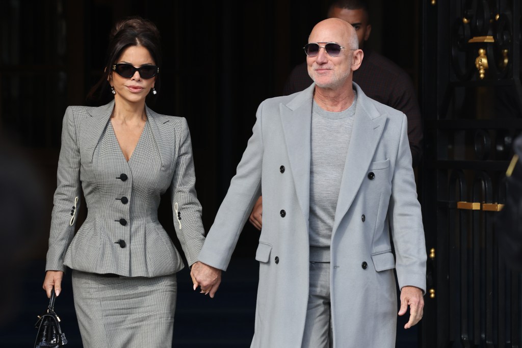 Jeff Bezos, in a grey coat, grey sweater and grey pants, and Lauren Sánchez, in a grey skirt suit, leaving The Ritz during Paris Fashion Week.