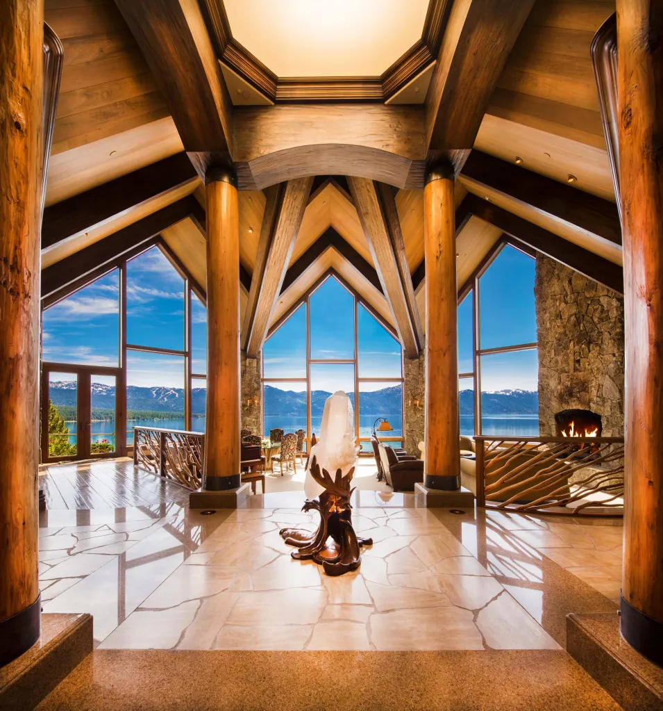 Interior of a large home with a panoramic view of Lake Tahoe and snow-capped mountains.