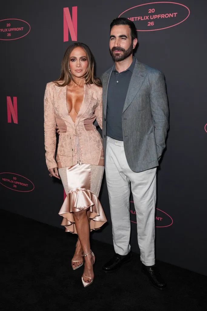 Jennifer Lopez and Brett Goldstein pose on the black carpet at the 2026 Netflix Upfront event.