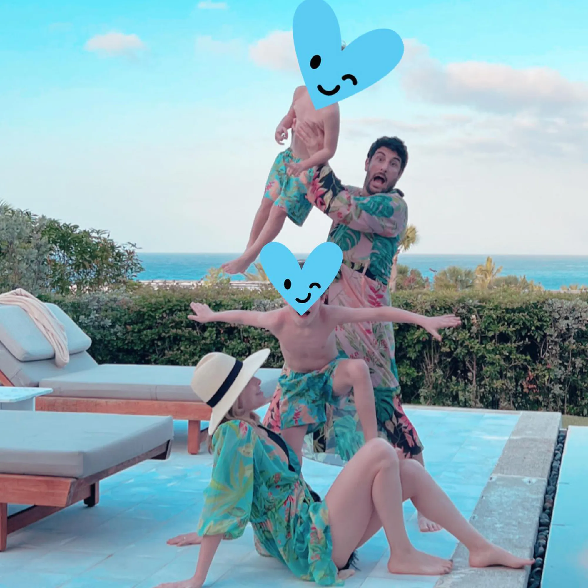 Jenny Mollen, Jason Biggs, and their two sons playing by a pool with the ocean in the background.