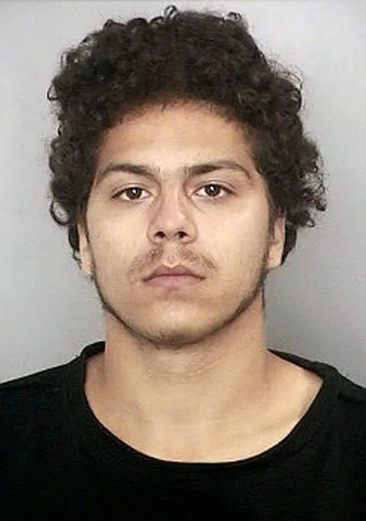 Mugshot of Jeromie Cancel, a young man with curly dark hair and a faint mustache and beard, wearing a black t-shirt.