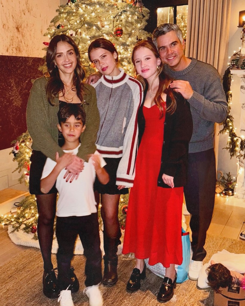 Jessica Alba, Cash Warren, and their three children standing in front of a Christmas tree.