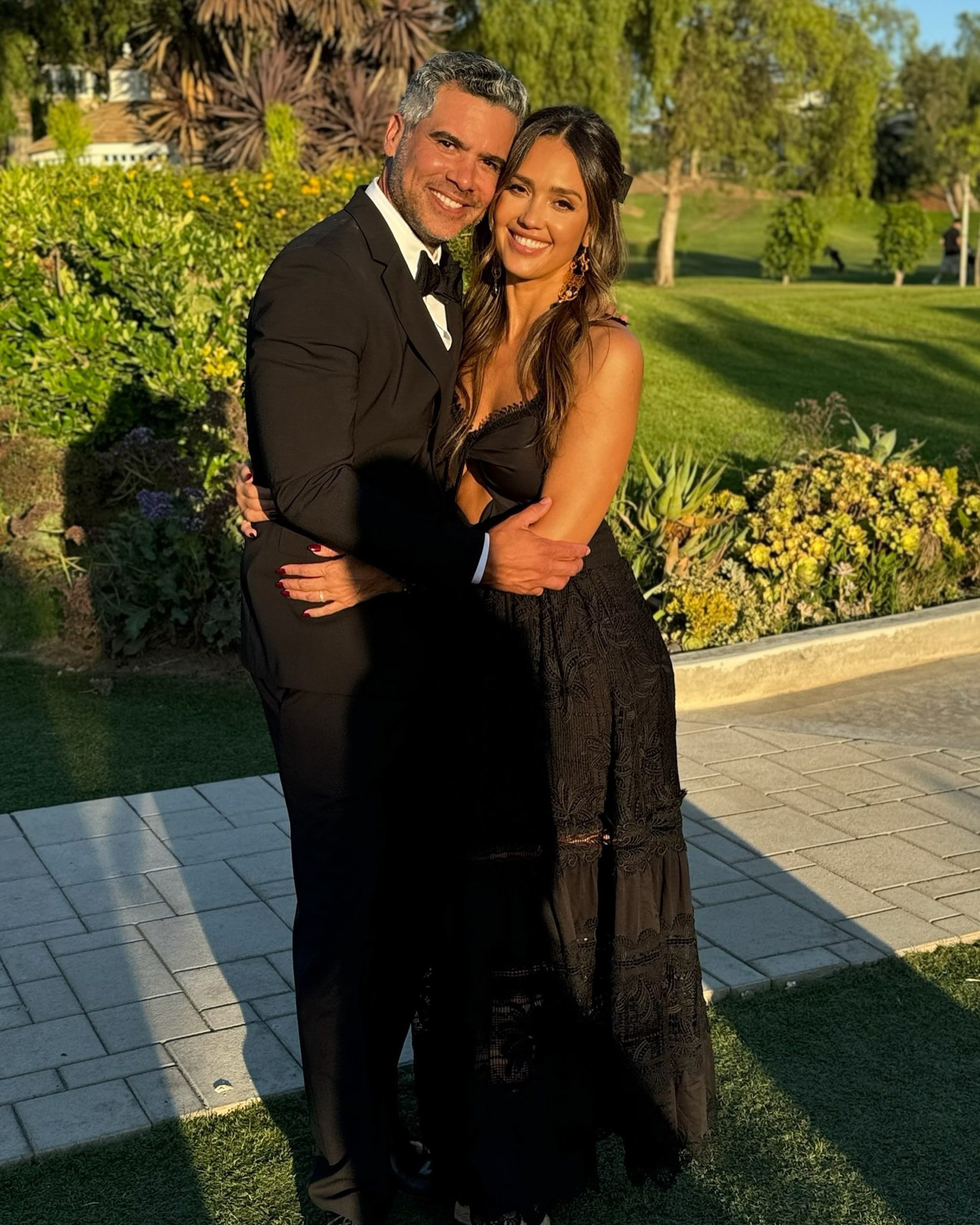 Jessica Alba and Cash Warren smiling and embracing outdoors.