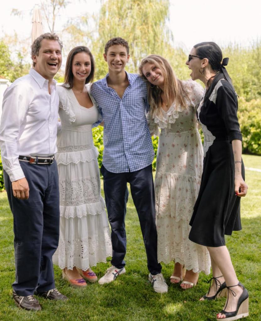 Jill Kargman and her family standing in a grassy area, smiling.