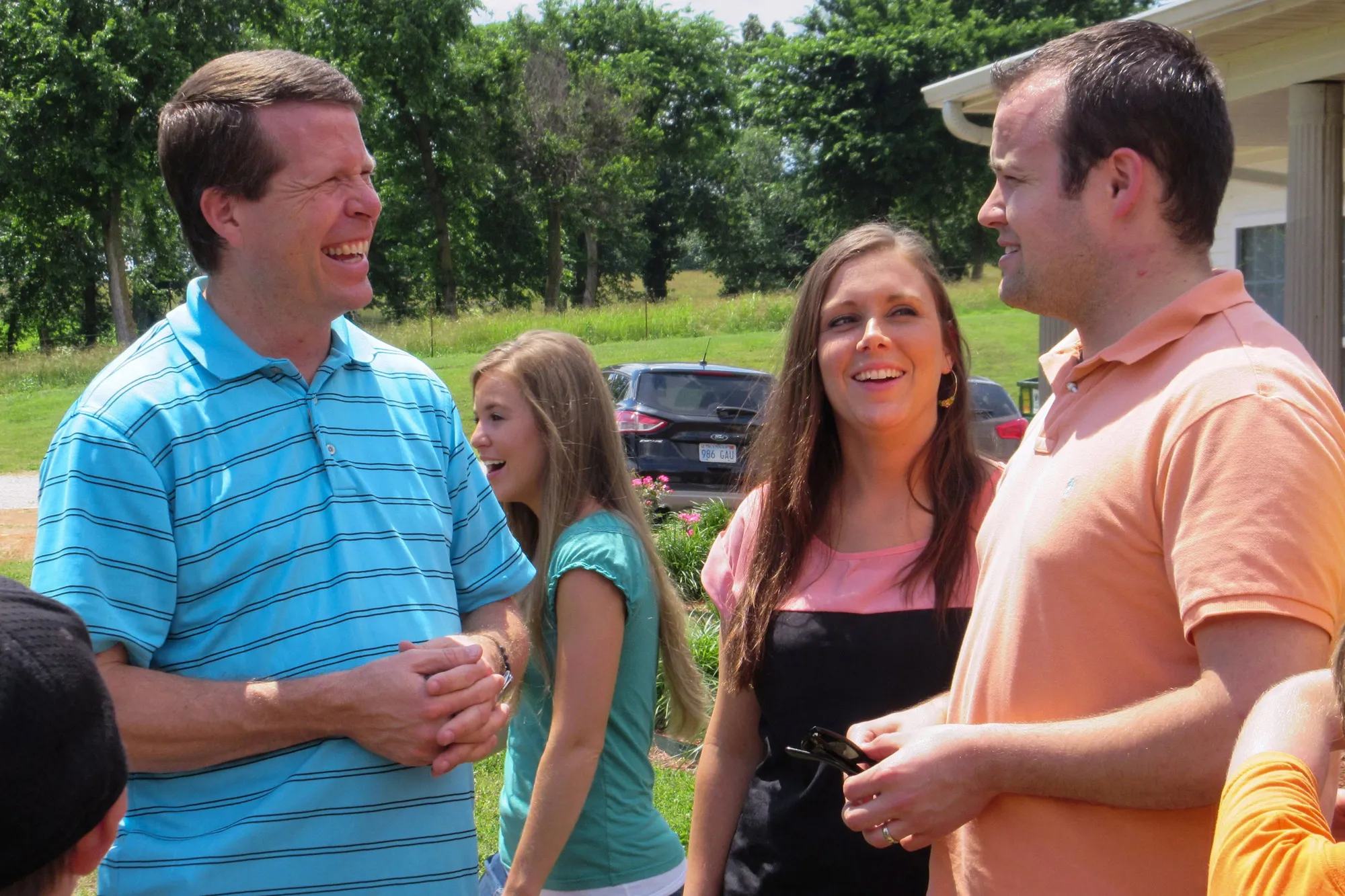 Jim Bob Duggar, wearing a blue striped polo, standing with his son Josh, his daughter Jill, and another woman.