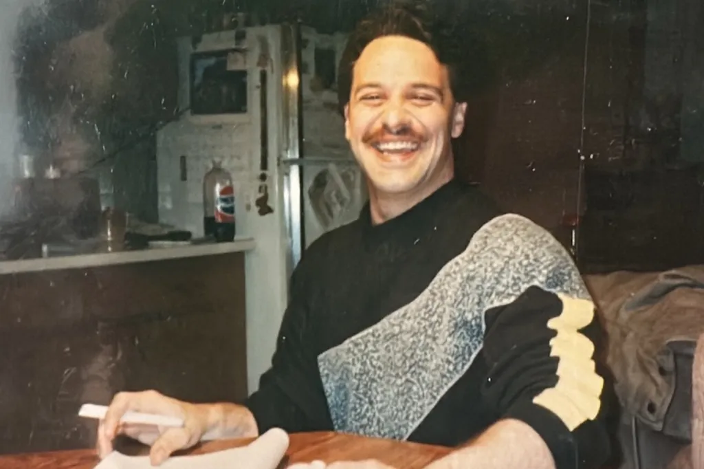John Pisano Jr. smiling and holding a cigarette.
